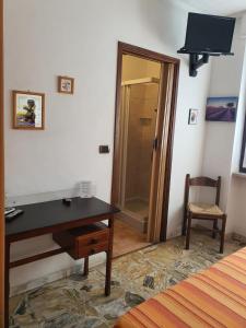 a bedroom with a desk and a door to a shower at Hotel Isolabella in Bussoleno