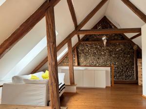 an attic room with a white couch and wooden beams at Weinkellerurlaub Röschitz in Roggendorf