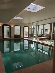 a large swimming pool in a building with windows at Hostellerie de la Pointe Saint-Mathieu - SPA & Restaurant in Plougonvelin