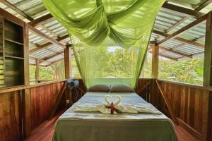 a bedroom with a bed with a bow on it at Casa Aire Libre - Jungle immersion - Natural pool - Waterfall in Puerto Jiménez