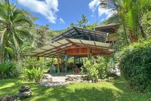 a house with a wooden structure in a garden at Casa Aire Libre - Jungle immersion - Natural pool - Waterfall in Puerto Jiménez +31 photos