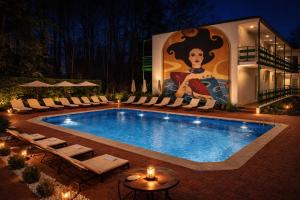a swimming pool with chairs and a painting on the side of a building at Forest Park Kiten in Kiten