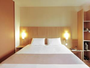 a bedroom with a large white bed with two pillows at ibis Birmingham Centre New Street Station Hotel in Birmingham +75 photos