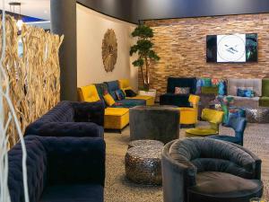a living room with couches and chairs and a tv at Mercure Bordeaux Aéroport in Mérignac