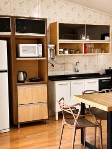 a kitchen with white cabinets and a table with chairs at Casa Chapadeira in Colinas Do Sul
