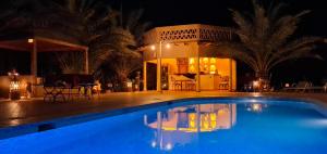 a swimming pool in front of a house at night at Oasis Tilogui-Luxury Hotel Restaurant and Desert Excursions In Zagora in Zagora