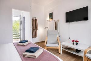 a white room with a tv and a chair at Karavaki apartments in Keri