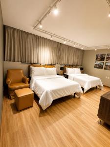 a hotel room with two beds and a chair at ibis Catanduva in Catanduva +63 photos