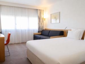 a hotel room with a large bed and a couch at Novotel Nantes Centre Gare in Nantes