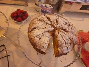 a cake on a plate on a table with fruit at Villa Olympia in Durrës