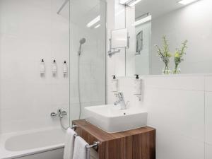 a white bathroom with a sink and a shower at Nemzeti Hotel Budapest - MGallery Collection in Budapest +74 photos