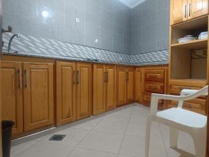 a kitchen with wooden cabinets and a white chair at Centre boukidan in Al Hoceïma +20 photos