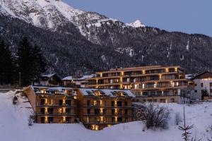 duży budynek w śniegu przed górą w obiekcie VAYA St Anton inklusive St Anton Mobilitätskarte w mieście Sankt Anton am Arlberg