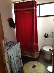 a bathroom with a red shower curtain and a toilet at Casa punta de lobos in Pichilemu