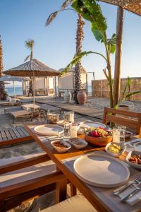 a wooden table with plates of food on the beach at Koi otel in Ayvalık