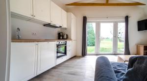 a kitchen with white cabinets and a couch in a room at Ottos Ferienhäuser in Rabenkirchen-Faulück
