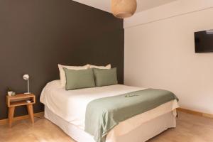 a bedroom with a large white bed with green pillows at DEPARTAMENTO en MENDOZA centro, moderno y cálido, Parking - Lavandería in Mendoza