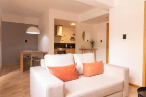a living room with a white couch with two orange pillows at DEPARTAMENTO en MENDOZA centro, moderno y cálido, Parking - Lavandería in Mendoza