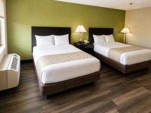 two beds in a hotel room with green walls at Studio Lodge of Augusta in Augusta