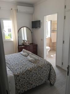 a bedroom with a bed and a mirror and a bathroom at Vila les Roses Quartos Jardim e Montanha in Porches