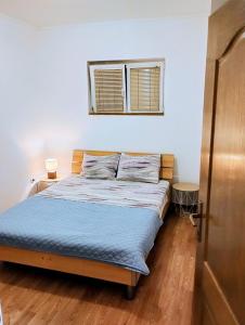 a bedroom with a bed with blue sheets and a window at Apartment Bay View in Kotor
