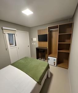 a small bedroom with a bed and a desk at Pousada Beach in Capão da Canoa