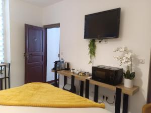a living room with a tv on a wall with a table at Chambre indépendante in Le Vigan