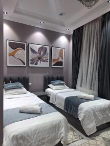 a bedroom with two beds and paintings on the wall at Light guest house in Samarkand +42 photos