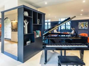 a room with a piano and a book shelf at Hotel De Bourbon Grand Hotel Mercure Bourges in Bourges