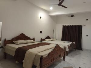 two beds in a bedroom with a ceiling at SHARDA PALACE Deoghar in Deoghar