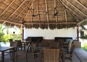 a restaurant with tables and chairs under a straw roof at Casa Flamingo in Bucerías