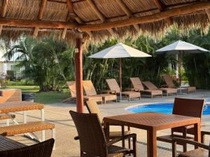 a patio with tables and chairs with umbrellas and a pool at Casa Flamingo in Bucerías