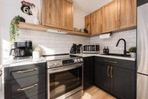 a kitchen with black appliances and wooden cabinets at Condo and Spa - Le Saloon Nordik in Saint Come
