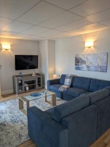 a living room with a blue couch and a tv at Le Repere, Beach, Whales, and Ferry in Saint-Siméon
