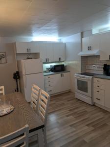 a kitchen with white appliances and a table and a table and chairs at Le Repere, Beach, Whales, and Ferry in Saint-Siméon