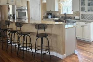 a kitchen with a island with four bar stools at Glen Eagle Kingfisher Suite in Colorado Springs +4 photos