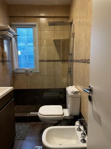 a bathroom with a toilet and a sink and a window at House51 "ubicado a solo 3 cuadras de la playa en pleno centro de Rada Tilly" in Rada Tilly