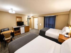 a hotel room with two beds and a television at Ste Anne Hotel in Sainte Anne-des-Chênes