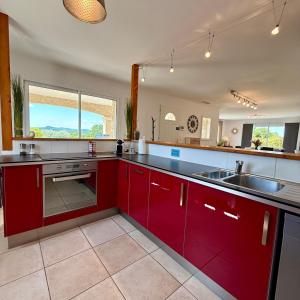 a kitchen with red cabinets and a sink at Villa Énalia in Barjac +22 photos