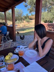 a woman sitting at a table with her hands on her face at Villa Rosa in Surrau in Arzachena