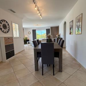 a dining room and living room with a table and chairs at Villa Énalia in Barjac
