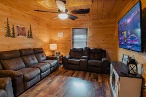 a living room with leather couches and a flat screen tv at The Burrows in Sevierville