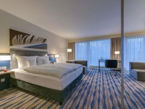 a hotel room with a large bed and a desk at Mercure Hotel am Entenfang Hannover in Hannover +64 photos