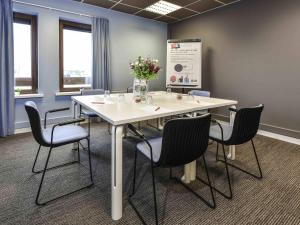 a conference room with a white table and chairs at ibis Charleroi Airport Brussels South in Charleroi