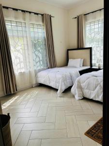 two beds in a room with windows and a tiled floor at Hazina Homes in Boma la Ngombe
