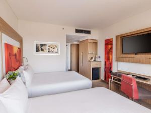 a hotel room with two beds and a flat screen tv at Novotel Sydney Olympic Park in Sydney +67 photos