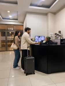 a man and a woman standing at a counter in an airport at Origen Apart-Hotel in Santiago
