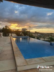 a large swimming pool with a sunset in the background at Villa Maze Suites - Canoa Quebrada in Aracati
