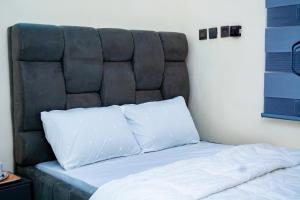 a bed with a black headboard and two white pillows at Ramlat Service Apartment in Ilorin