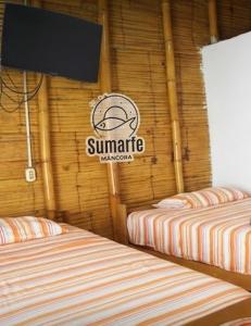 two beds in a room with a sign on the wall at Sumarfe in Máncora